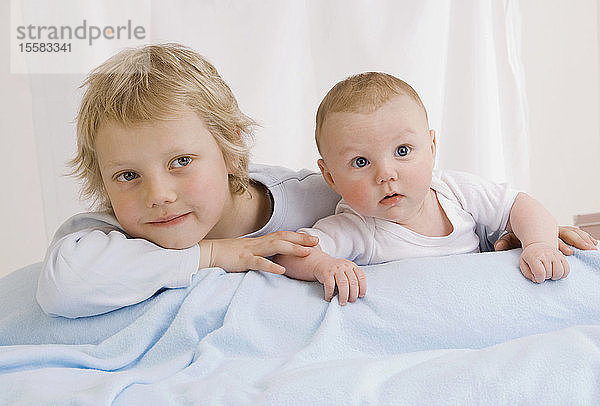 Deutschland  Junge (2-3 Jahre) und Baby Junge (2-5 Monate) im Bett liegend