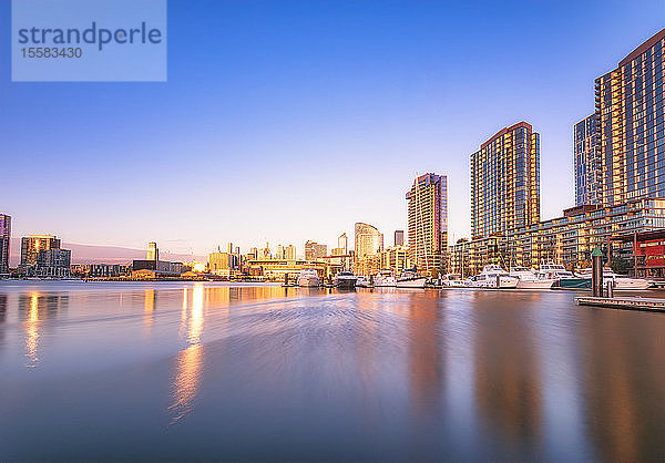 Beleuchtete Gebäude am Fluss in den Docklands von Melbourne gegen den blauen Himmel in der Abenddämmerung  Victoria  Australien