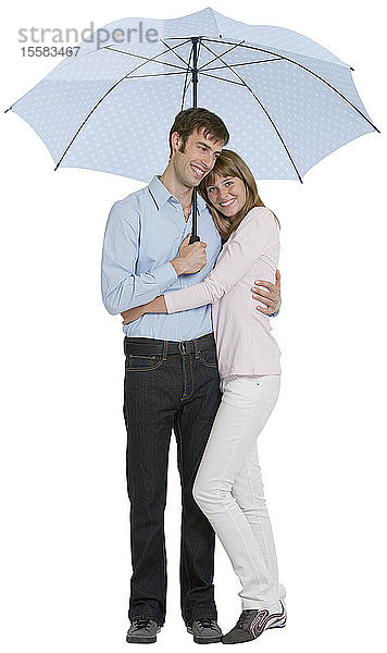 Paar umarmt sich unter einem Schirm  lächelnd