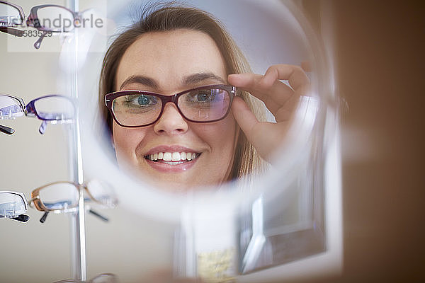 Frau beim Optiker  die eine Brille anprobiert