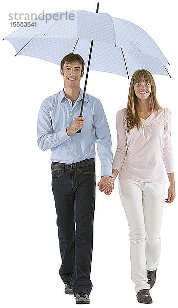 Lächelndes Paar beim Spaziergang mit Regenschirm