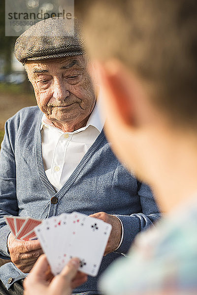 Älterer Mann und Enkel spielen Karten