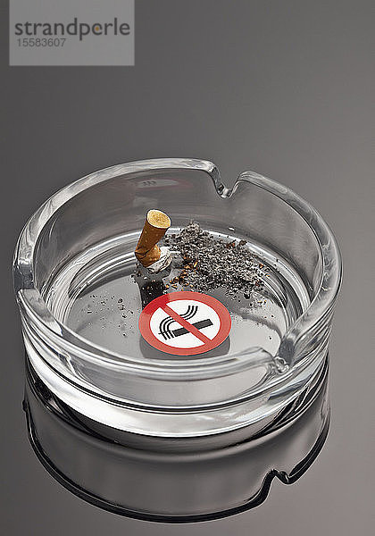 Zigarette im Aschenbecher mit Rauchverbotszeichen