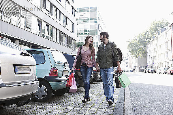 Deutschland  Köln  Junges Paar mit Einkaufstaschen in der Nähe des Parkplatzes  lächelnd