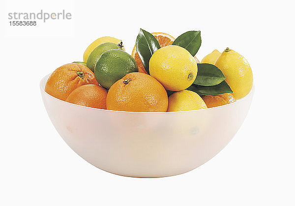 Schale mit frischen Orangen und Zitronen auf weißem Hintergrund