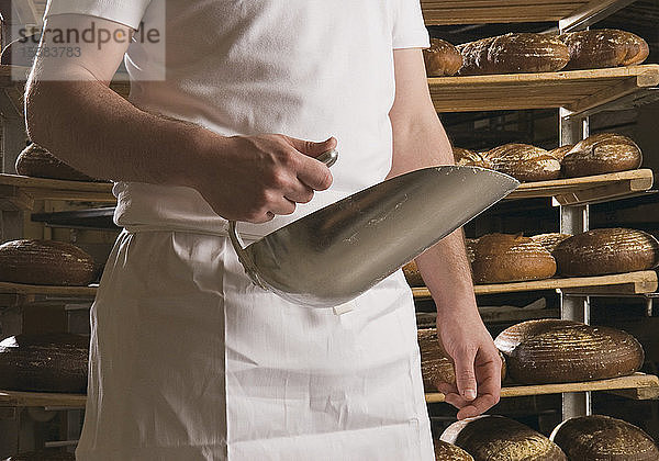 Deutschland  Bäcker mit Schaufel und Laib Brot im Regal