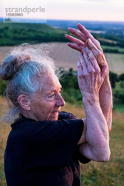 Ältere Frau  die an einer Yogastunde an einem Berghang teilnahm.