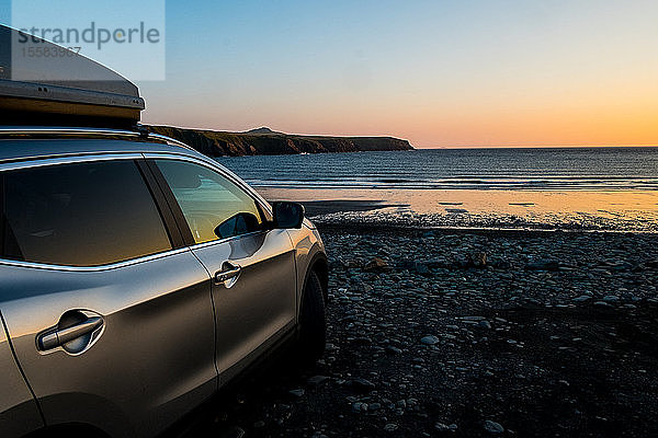 Auto  das bei Sonnenuntergang an einem Strand an der Küste von Pembrokeshire  Wales  Großbritannien  geparkt ist.