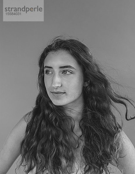 Schwarz-Weiß-Porträt eines hübschen sechzehnjährigen Mädchens  das vom Wind durch ihr langes gewelltes Haar geweht wird