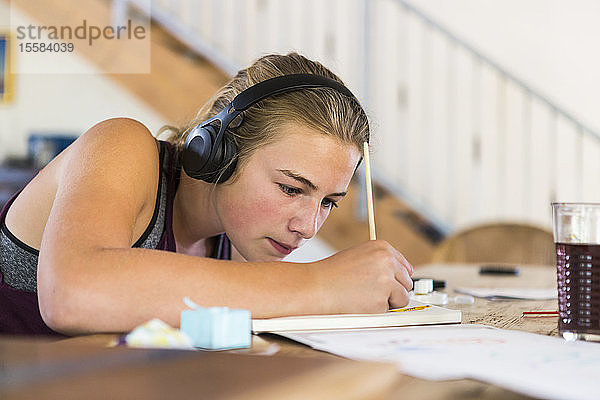 13-jähriges Mädchen zu Hause trägt Kopfhörer beim Malen