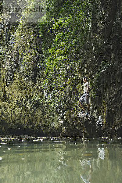 Mann ohne Hemd steht auf einem Felsen im See bei den Klippen in Krabi  Thailand
