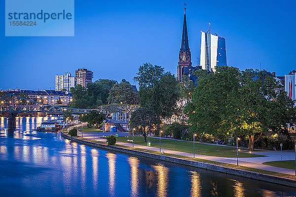 Kirche und Bürotürme am Fluss bei Sonnenuntergang in Frankfurt  Deutschland