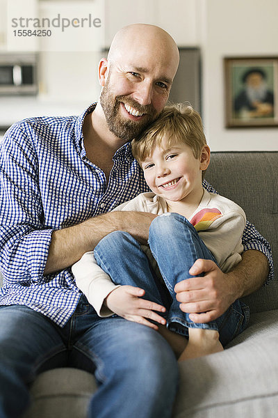 Vater und Sohn lächelnd auf dem Sofa