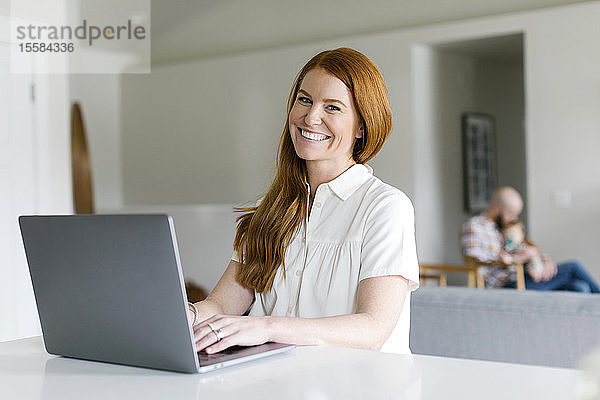 Lächelnde Frau benutzt Laptop zu Hause