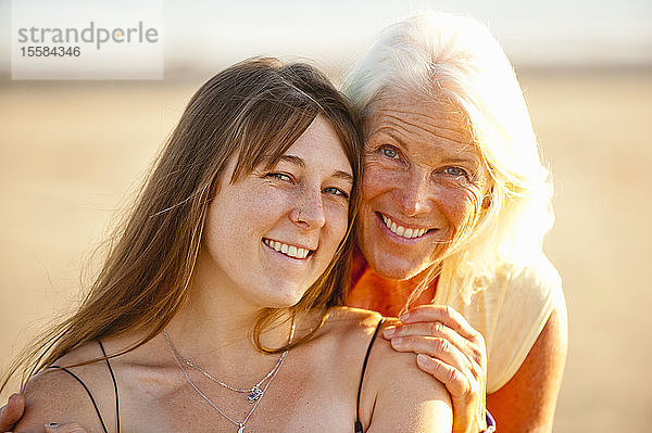 Porträt von Mutter und erwachsener Tochter lächelnd am Strand