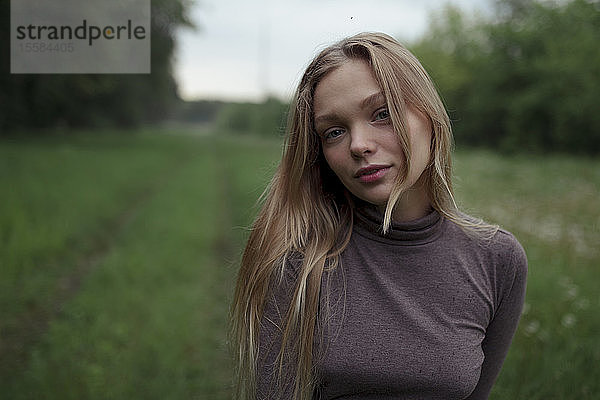 Porträt einer jungen Frau mit blondem Haar auf einem Feld