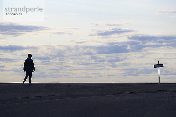 Silhouette einer Frau  die bei Sonnenuntergang spazieren geht
