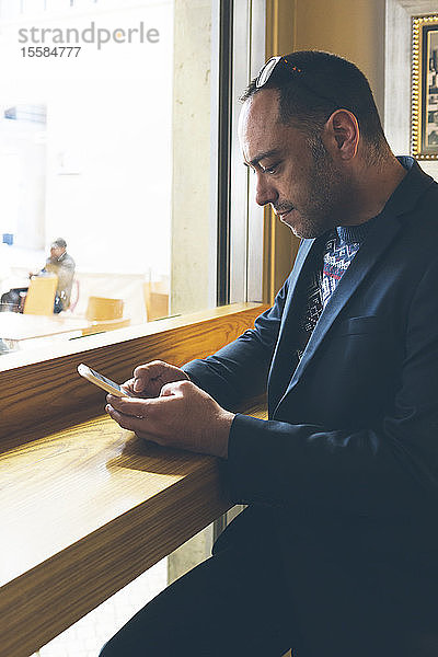 Mann benutzt Smartphone in einem Cafe