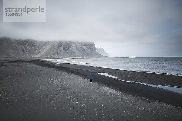 Mann spaziert am schwarzen Sandstrand in KirkjubÂµjarklaustur  Island