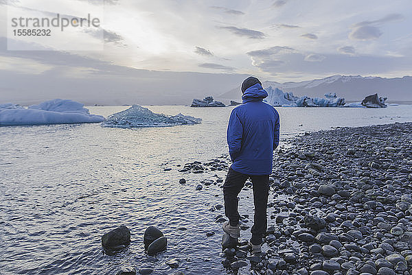 Mann in blauem Mantel am Gletschersee Jokulsarlon in Island