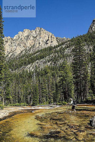 Eine Frau watet durch einen Fluss bei den Sawtooth Mountains in Stanley  Idaho  USA