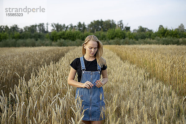 Junge Frau im Overall in einem Weizenfeld