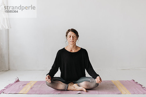 Frau sitzt in Lotus-Pose im Yoga-Studio