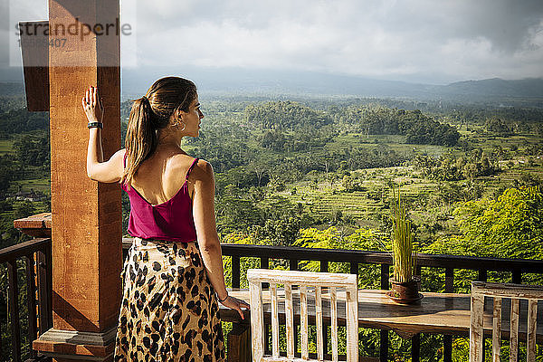 Junge Touristin  die vom Hotelbalkon auf die Landschaft schaut  Bali  Indonesien