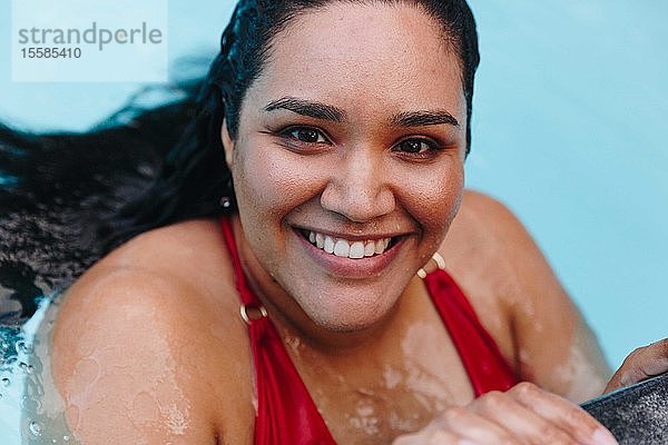 Mittlere erwachsene Frau mit nassem Haar  die sich am Swimmingpool im Freien festhält  Kopf- und Schulterporträt  Kapstadt  Südafrika