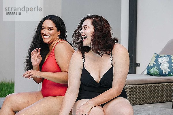 Zwei mittelgroße erwachsene Frauen sitzen zusammen lachend im Freibad  Kapstadt  Südafrika
