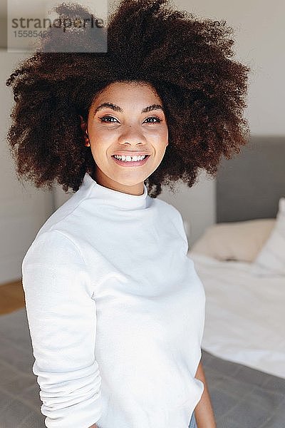 Glückliche junge Frau mit Afro-Frisur im Schlafzimmer  Portrait mit Taillenaufschlag