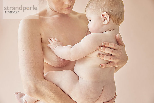 Nackte Mutter trägt nacktes Baby auf dem Arm