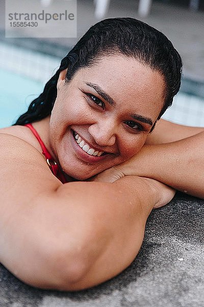 Mittelgroße erwachsene Frau mit nassem Haar  die am Swimmingpool im Freien lehnt  Kopf- und Schulterporträt  Kapstadt  Südafrika