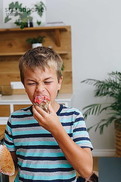 Junge beißt zu Hause in Cupcake