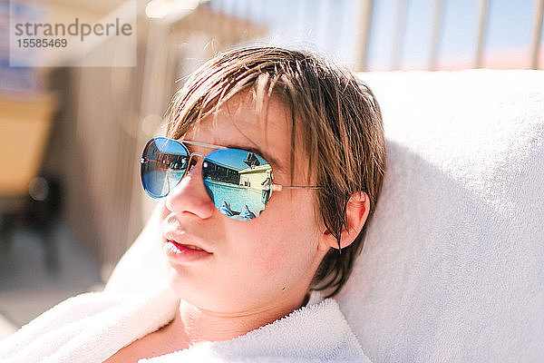Cooler Teenager-Junge mit spiegelbildlicher Sonnenbrille auf einer Sonnenliege am Hotelpool  Kopf und Schultern  Las Vegas  Nevada  USA