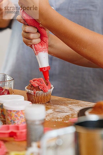 Handdekoration von Törtchen mit roter Glasur