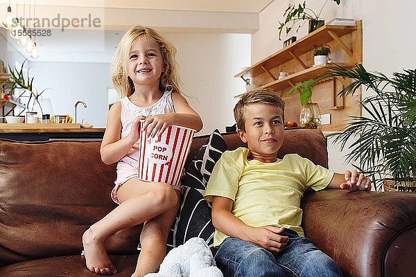 Kinder entspannen bei Popcorn auf dem Sofa zu Hause