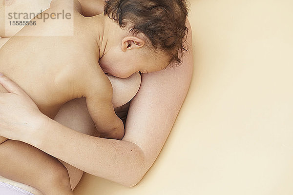 Nacktes Baby beim Saugen an der nackten Mutterbrust