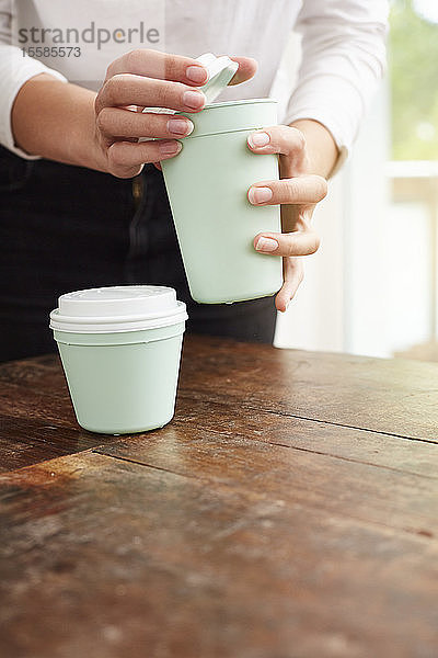 Frau benutzt wiederverwendbare Kaffeetasse