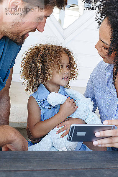 E-Learning für Paare mit Tochter auf Smartphone im Strandhaus