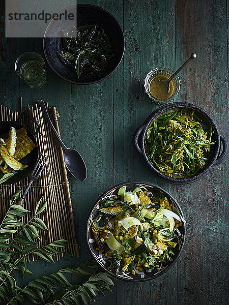 Rustikales Low-Key-Stillleben mit Schalen mit Curryblatt-Fischsalat und Thoran aus grünen Bohnen auf dem Tisch  Draufsicht