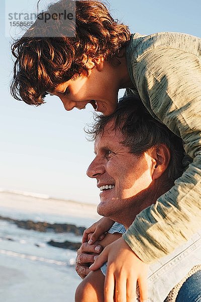 Vater reitet Sohn huckepack am Strand