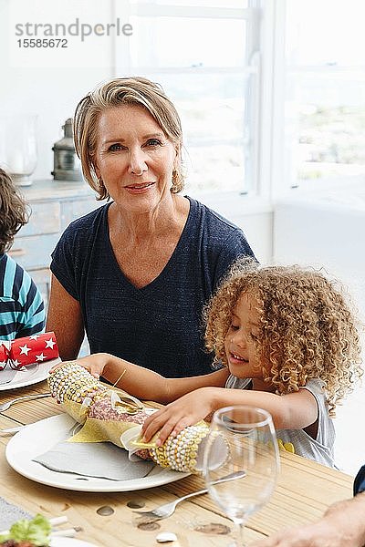 Frau mit Enkelin spielt mit Weihnachtsgebäck am Esstisch