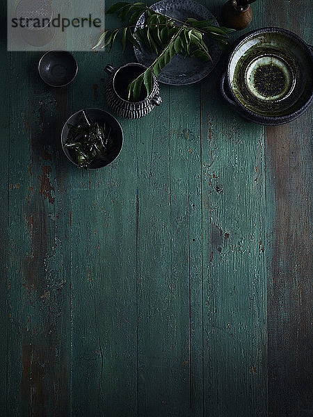 Rustikales Low-Key-Stillleben mit Schalen und Tasse auf grünem Holztisch  Draufsicht