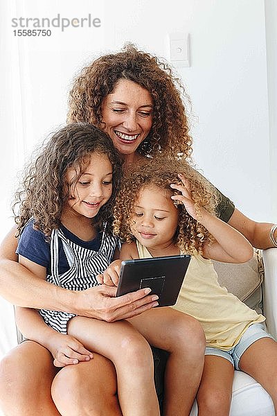 Mutter und Töchter benutzen digitales Tablett zu Hause