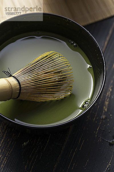 Stilleben der Zubereitung von Matcha-Tee mit Schneebesen in einer Schale Matcha-Tee  Nahaufnahme  Draufsicht