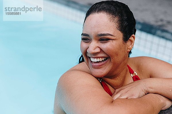 Mittelgroße erwachsene Frau mit nassem Haar lehnt am Swimmingpool im Freien und schaut über ihre Schulter  Kapstadt  Südafrika