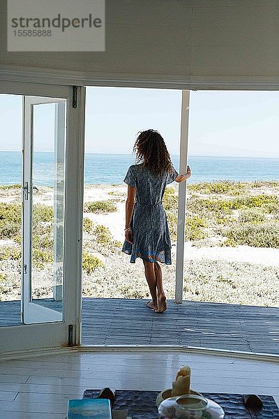 Frau genießt Meeresblick auf der Veranda des Strandhauses