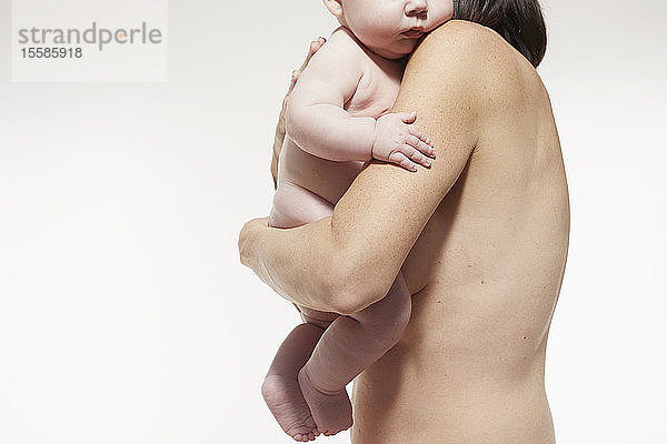 Nackte Mutter tröstet nacktes Baby  das an ihrer Brust liegt