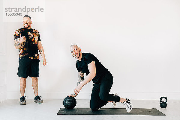 Mann zeigt dem Fitnesstrainer im Studio die Daumen hoch